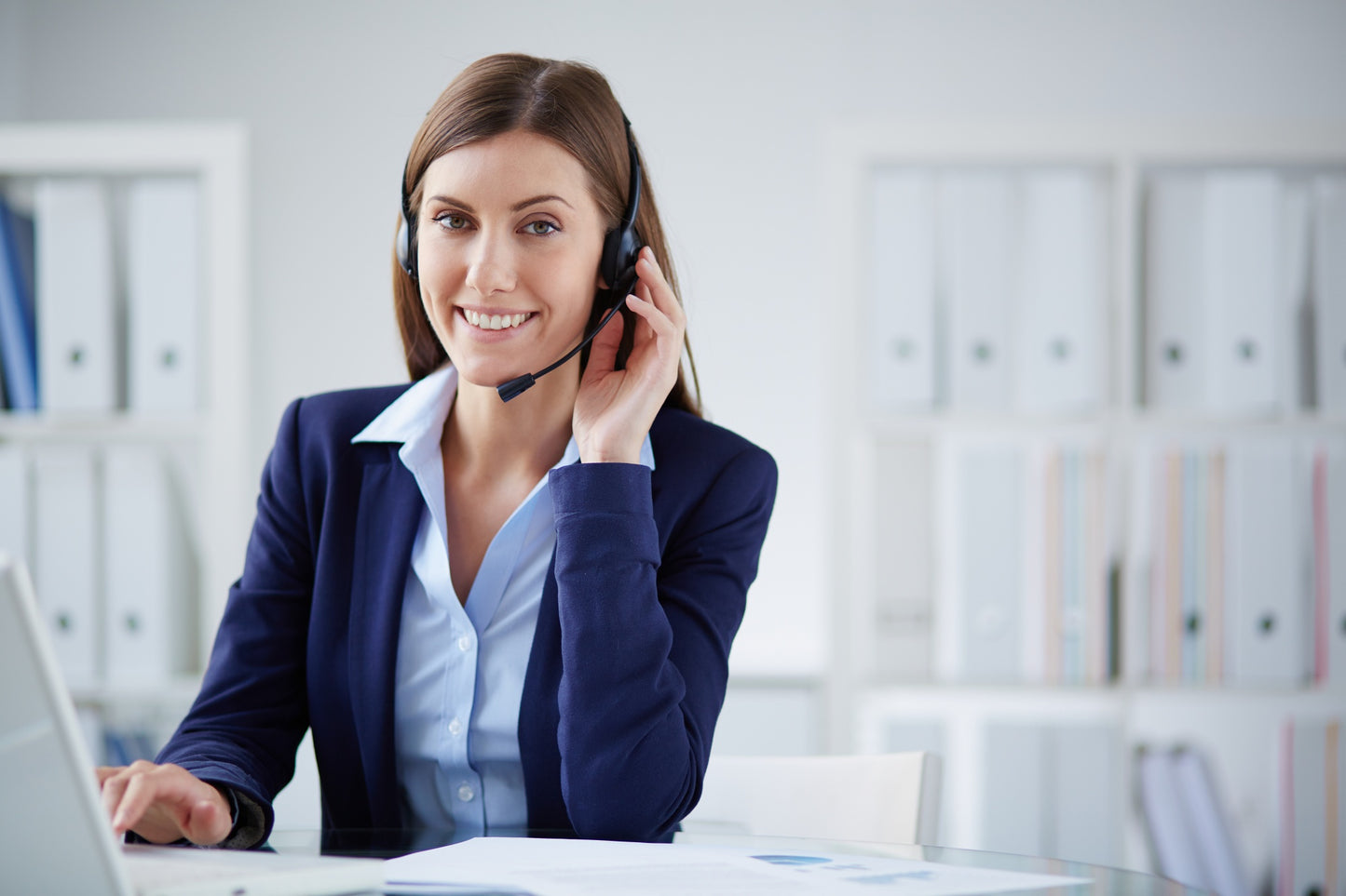 Woman wearing a headset and smiling at her desk in an office setting