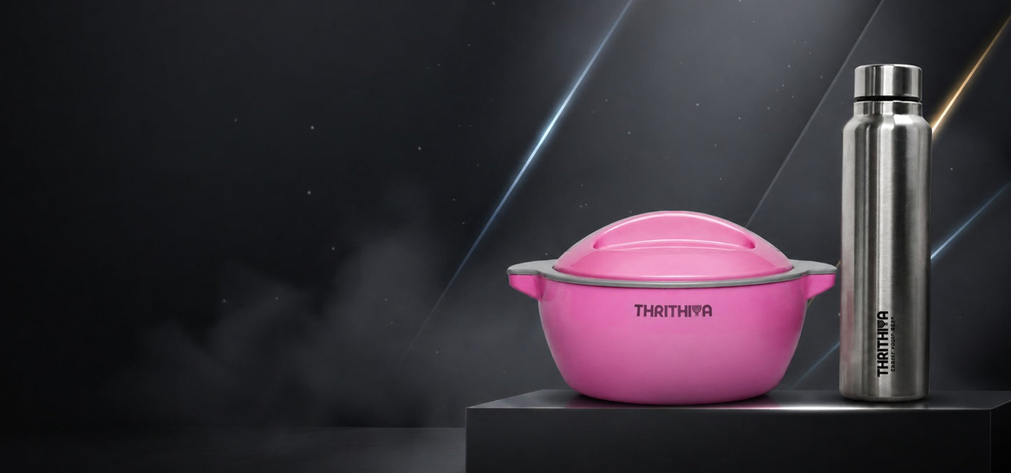A pink Thrithiya lidded bowl with gray handles sits next to a tall silver stainless steel bottle with a black cap on a dark pedestal against a dark studio background.